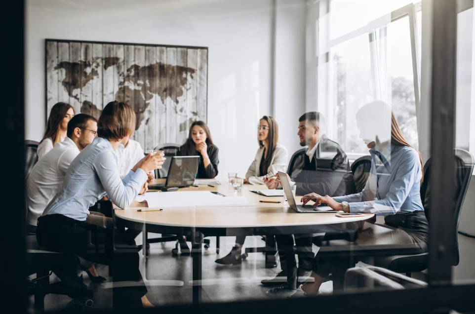 a team of people sitting at the desk with laptops and a world map on the wall