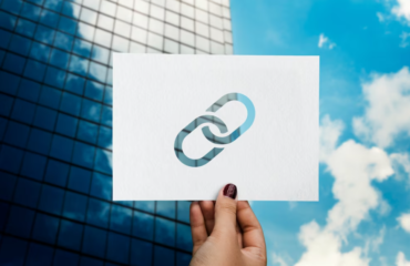 Hand holding the plain paper with a link on it in front of a skyscraper and cloudy sky